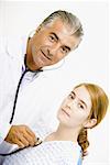 Portrait of a male doctor examining a young woman with a stethoscope