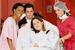 Two female doctors and a male doctor pushing a female patient on a hospital gurney