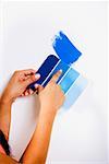 Close-up of a woman's hand holding color swatch against a wall