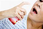 Gros plan d'une femme senior pulvérisation rince-bouche dans sa bouche