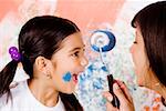 Close-up of a girl laughing with her mother holding a paint roller