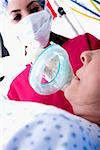 Low Angle View of putting eine Sauerstoffmaske auf ein Patient weiblich Chirurg