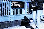 Low section view of a man passing in front of a subway sign