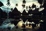 Reflection of huts and trees in water, Huahine Island, French Polynesia