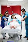 Male and a female doctor pushing a pregnant young woman lying on a stretcher