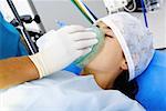 Surgeon's hand putting an oxygen mask on a female patient