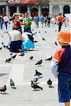 Vue arrière d'un garçon debout et en regardant des pigeons, Venise, Vénétie, Italie