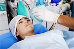 Des Chirurgen Hand setzen eine Sauerstoffmaske auf einer Patientin