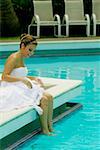 Side profile of a bride sitting at the poolside and smiling