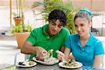 Close-up of a teenage girl and a young man eating salad and a wrap in a restaurant