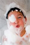 Close-up of a boy blowing soap suds in a bathtub