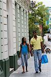 Jeune homme et une jeune adolescente, marchant sur le trottoir avec des sacs à provisions