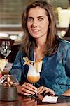 Portrait of a mid adult woman sitting in a restaurant and holding a glass of pina colada