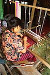 High angle view of a young woman weaving on traditional loom, Sukhothai, Thailand