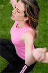 High angle view of a young woman sitting in the lotus position with her arms outstretched