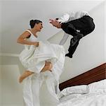 Flachwinkelansicht von einem frisch verheirateten Paar springen auf dem Bett