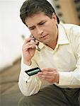 Close-up of a mature man talking on a mobile phone and holding a credit card