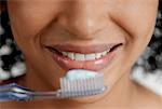 Gros plan d'une brosse à dents avec dentifrice en face de la bouche d'une jeune femme