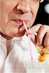 Close-up of a mid adult man drinking pina colada with a drinking straw