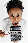 Portrait of a businesswoman pointing at a calculator with her mouth open