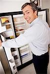 Portrait of a mature man standing near a refrigerator and smiling