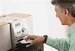 Side profile of a senior man inserting a CD into a CD player