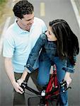 High angle view of a mid adult man helping a mid adult woman ride a bicycle