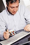 Close-up of a mature man holding a cup of coffee and doing a crossword puzzle