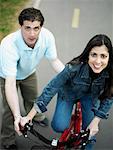 Vue d'angle élevé d'un homme adult milieu aidant un milieu tour de femme adulte une bicyclette