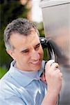 Close-up of a mid adult man talking on a pay phone