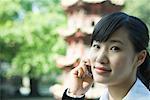 Woman using cell phone, pagoda in background, close-up