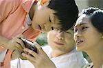 Boy with parents, mother holding digital camera, boy bending over to look