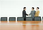 Business associates shaking hands in conference room