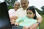 Girl and grandparents using laptop