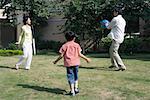 Family playing ball on grass, full length