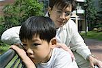 Father and son on bench, boy pouting