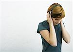 Young woman listening to headphones, white background