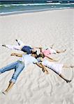 Family lying on sand, heads together and arms and legs out