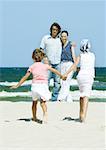 Family on beach, two girls walking hand in hand toward parents