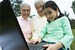 Girl using laptop while grandparents watch