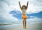 Girl jumping on beach, full length