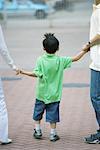 Boy holding parents' hands