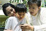 Boy with mother and father, father holding out cell phone for boy to see