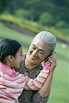 Girl with grandmother, holding cell phone to ear