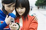 Two young women friends looking at cell phone together