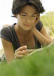 Woman lying in grass, reading book