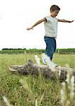 Boy walking on log, arms out, smiling