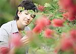 Woman looking at flower on shrub