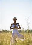 Woman standing in prayer position in field