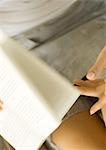 Woman turning pages of book, partial view